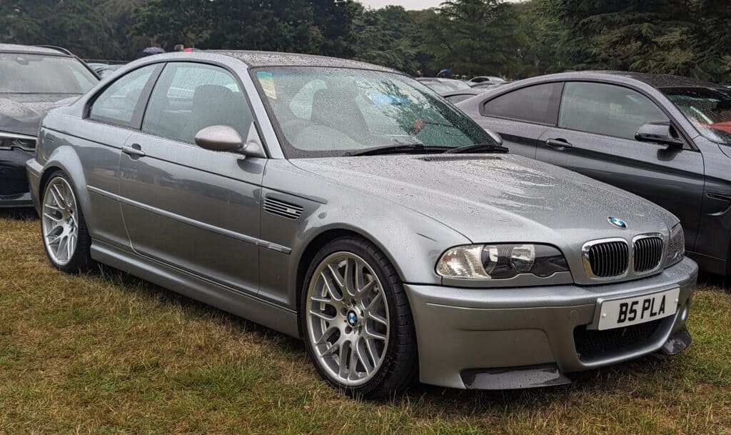 A gray E46 BMW M3 CSL parked on a lawn.
