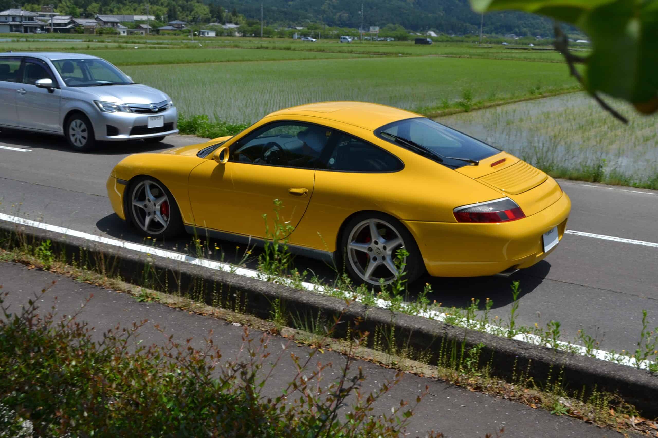 A rear three-quarter view of a yellow Porsche 911 996.