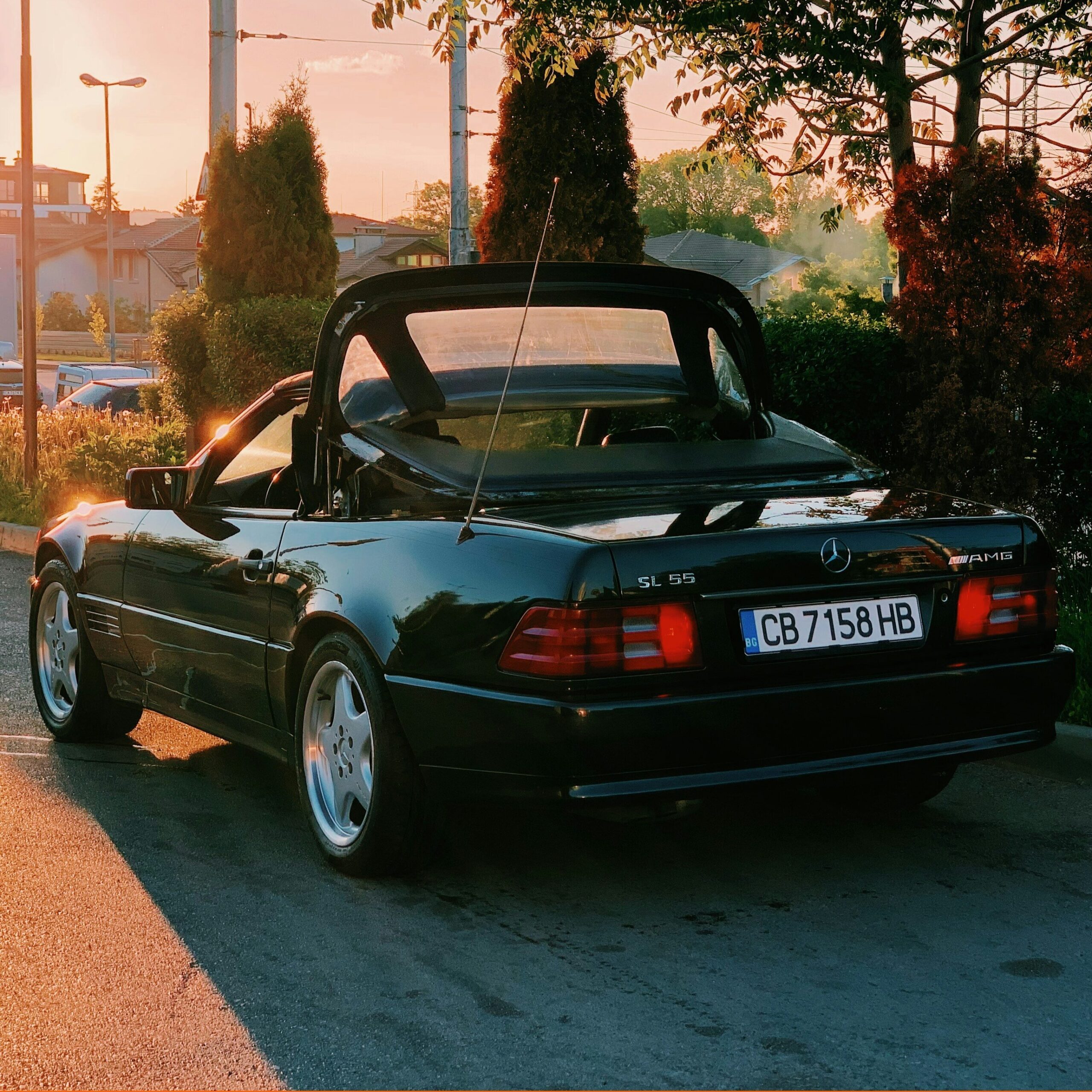 Black Mercedes R129 SL55 with its soft top opening.