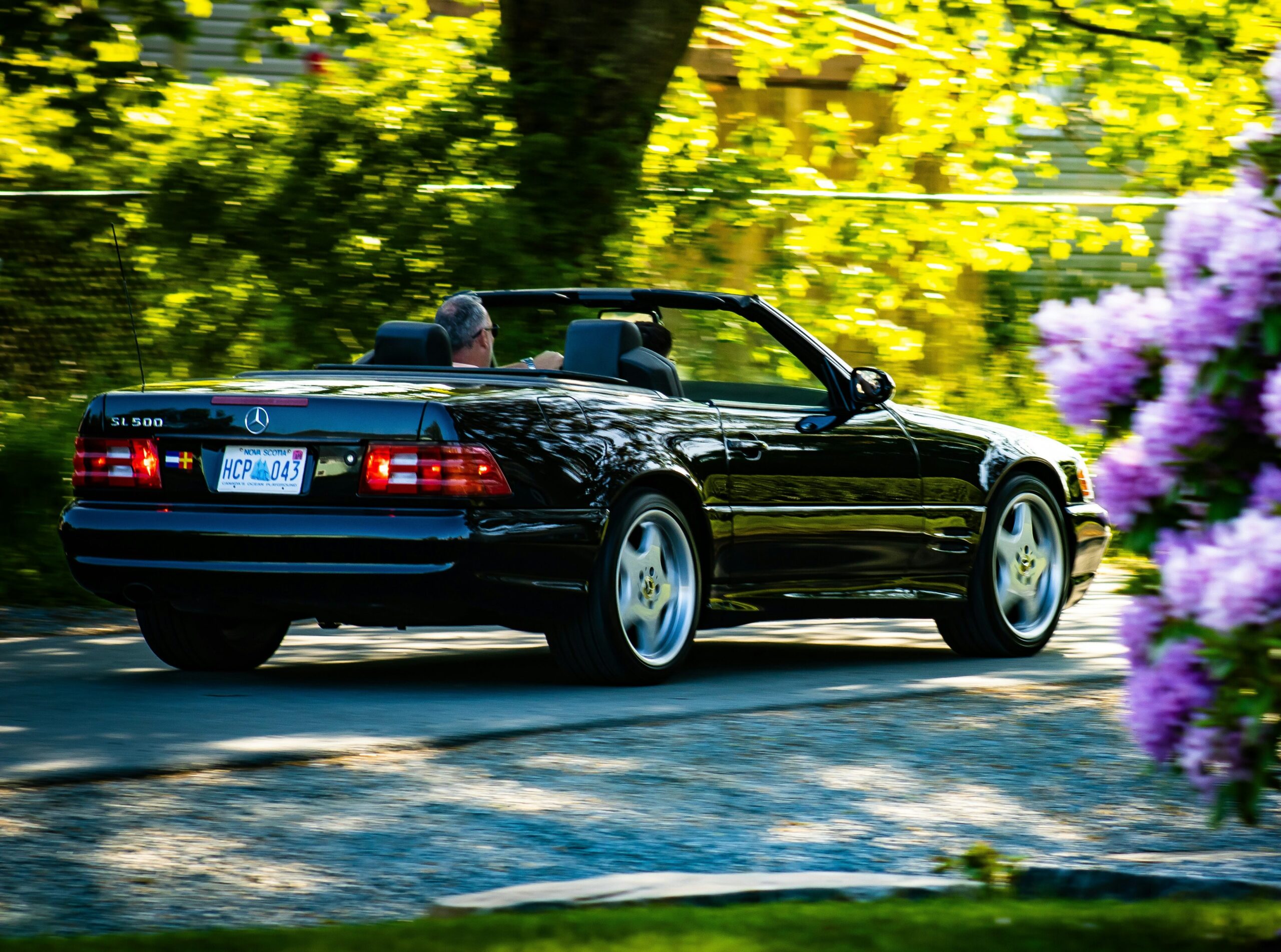 A black Mercedes R129 driving down the road.