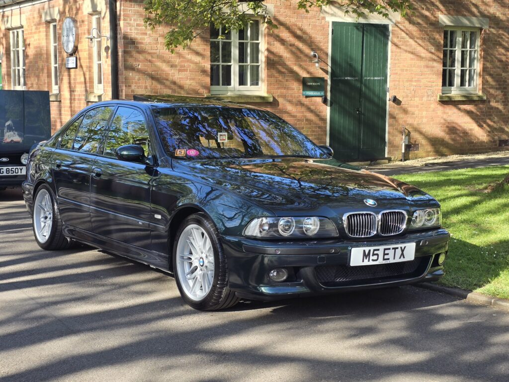  A dark green E39 BMW M5 parked on a street.
