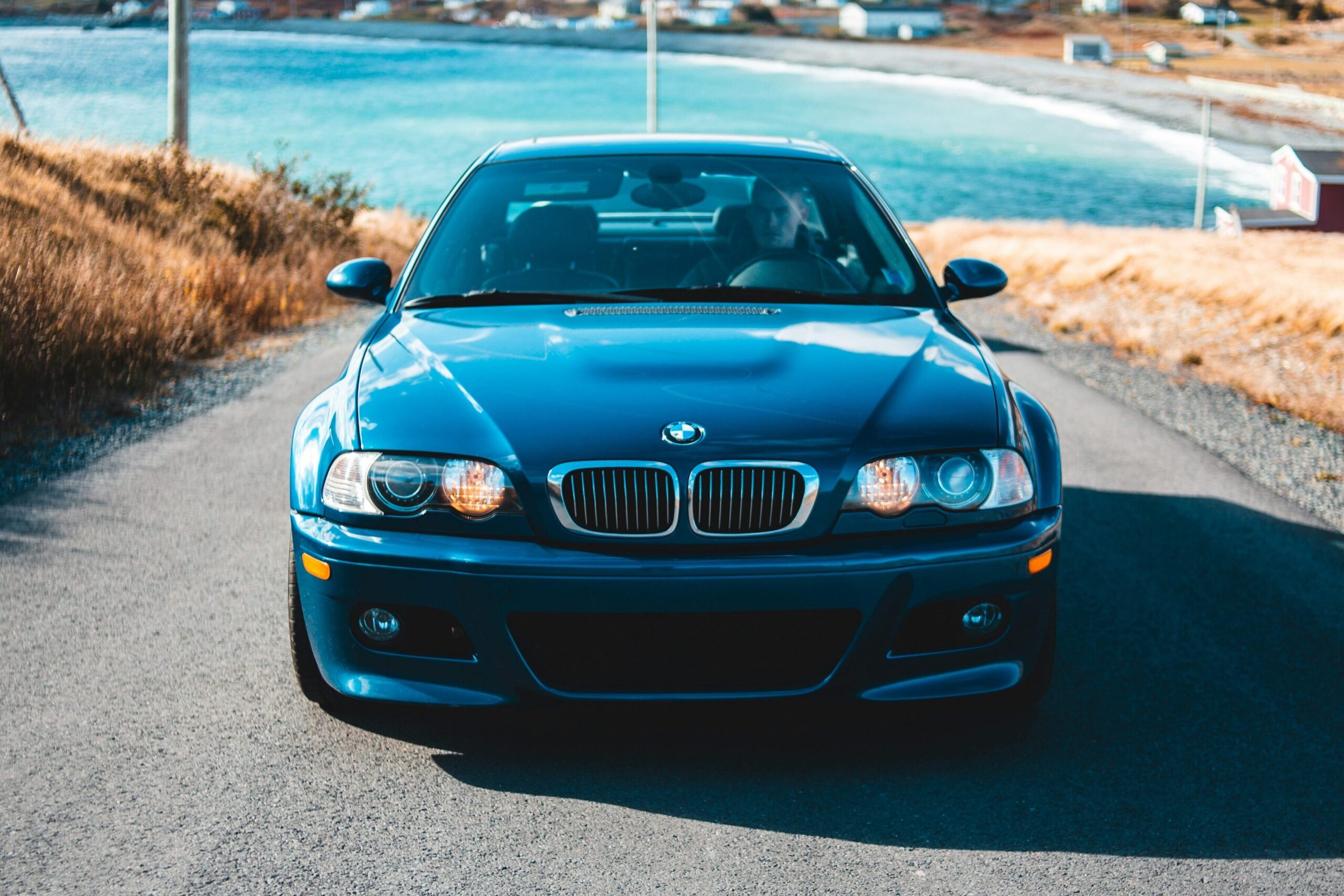 A front-end view of a dark blue BMW E46 M3 near water.