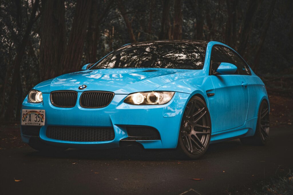 A blue BMW E92 M3 parked in front of woods.