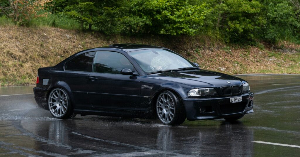 A black BMW E46 M3 driven sideways on a wet road.