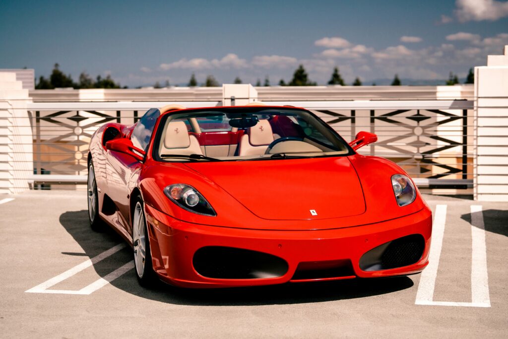 A red Ferrari F430 Spyder parked in a rooftop parking lot.
